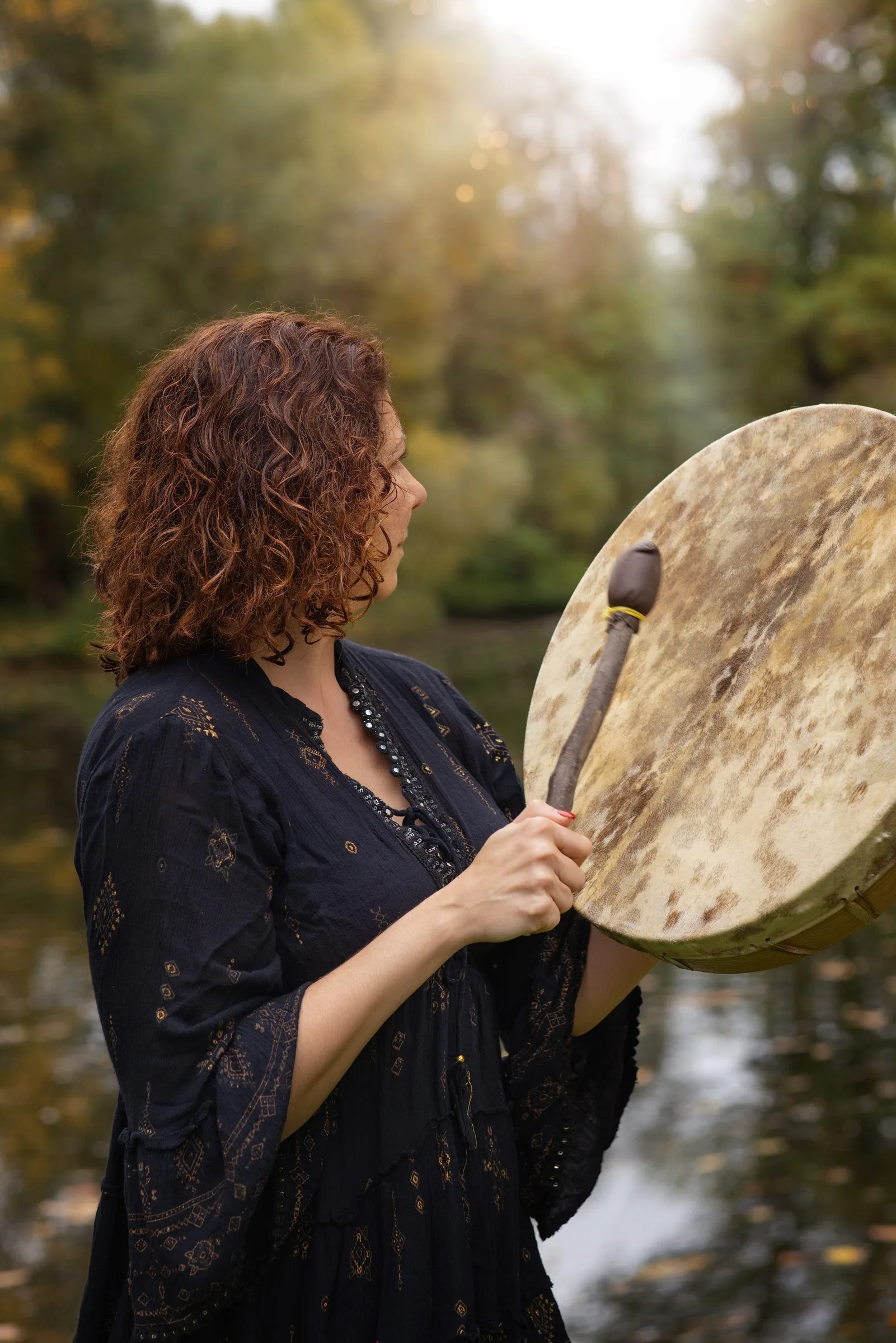 Kamila im Profil mit ihrer Schamanentrommel am Weiher